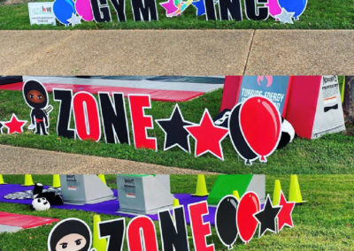 Three YL Hampton signs - "Gym Inc" and two "Zone" signs. "Gym Inc" is surrounded by blue and pink balloon cutouts, stars and a dancer. Both "Zone" signs have red and black balloons and stars with a ninja character.