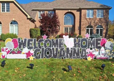 YL Expressions sign - "Welcome Home Giovanna". Glittery black letters surrounded by glittery pink, gold and silver elements - balloons, baby, princess, "#welcomebaby", ballet shoes