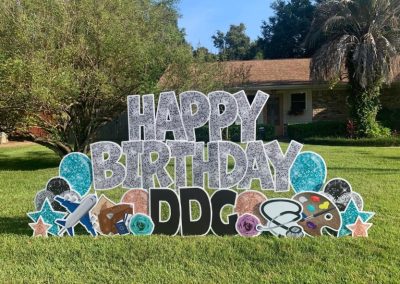 YL Pensacola sign - "Happy Birthday DDG". Disco ball-patterned silver letters surrounded by blue and black disco balls and stars, travel, doctor and artist symbolism.