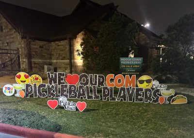 YL McKinney sign - "We Heart Our COM Pickleball Players". Glittery bold black letters surrounded by hearts, margaritas, tacos, pickleball symbols.