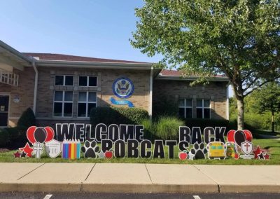 YL Little Miami sign - "Welcome Back Bobcats". Bold black text surrounded by school paraphernalia, school emblems