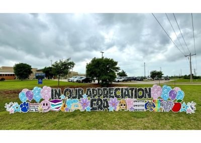 Lawn Sign in front of School: "In Our Appreciation Era (black sparkles). The rest in pastel pink, blue, and purple sparkles - balloons, stars, happy face, flowers, hearts, We Love You; Apple, Crayons, Mascot, Swiftie sign, Heart with two hands, guitar, books, paw, megaphone emoji's, mascot (panther), Teachers, Thanks for Everything You Do! sign.