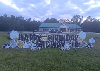 YL Savannah sign - "Happy Birthday Midway!" Glittery black letters and gold and silver balloons, candles, stars, "We Love You" heart